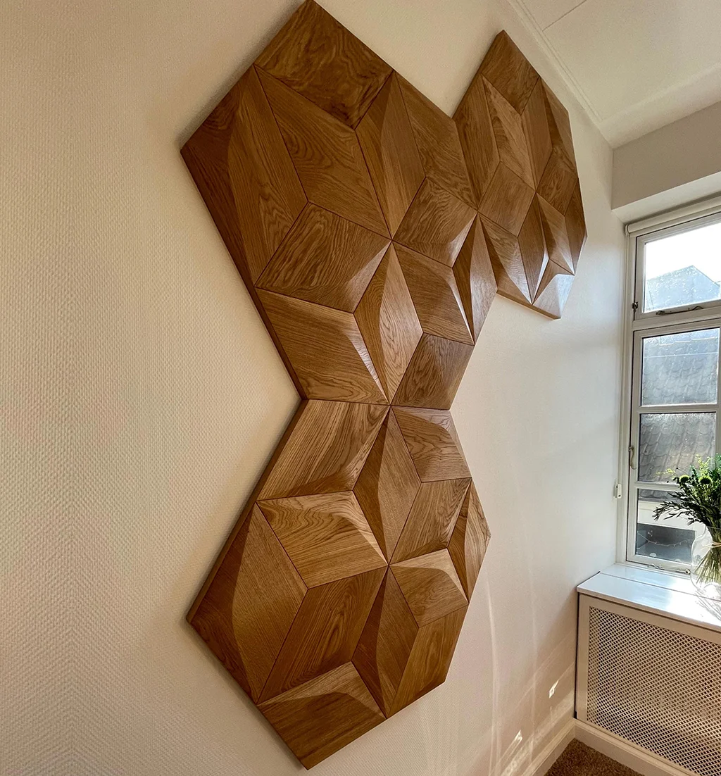 Modern geometric wall decor made of 3D oak diamond-shaped wood panels arranged in a unique pattern on a white wall.