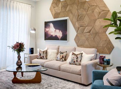 Phòng khách ấm cúng với bức tường nhấn bằng gỗ mộc hình học phía trên chiếc ghế sofa màu be, mang lại sự ấm áp và chiều sâu cho không gian